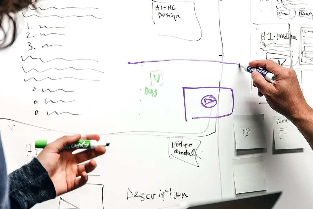 Persons hand-drawing on a whiteboard.